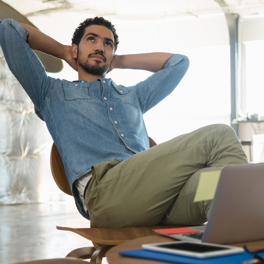 Man met laptop leunt achterover